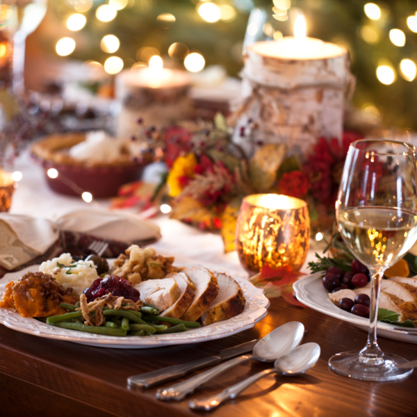 Festive dinner table with sliced turkey, green beans, cranberry sauce, mashed potato and a glass of white wine