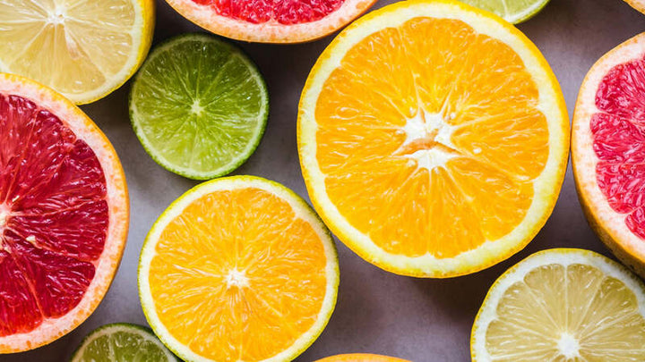 Sliced citrus fruits including oranges, limes, lemons and grapefruit arranged on a pale surface