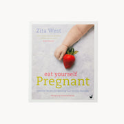 Book cover of 'Eat Yourself Pregnant' by Zita West with a hand holding a strawberry.