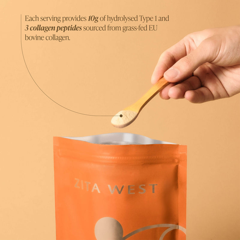Hand holding a spoon with collagen powder over an orange Zita West package on a beige background.