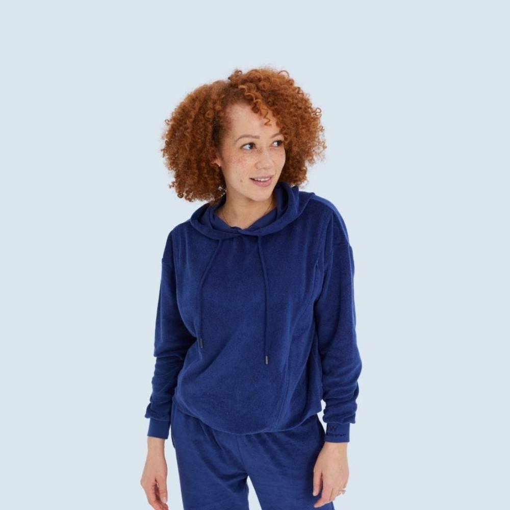 A woman wearing a navy blue hooded top and matching pants made of organic cotton, designed for postnatal wear.