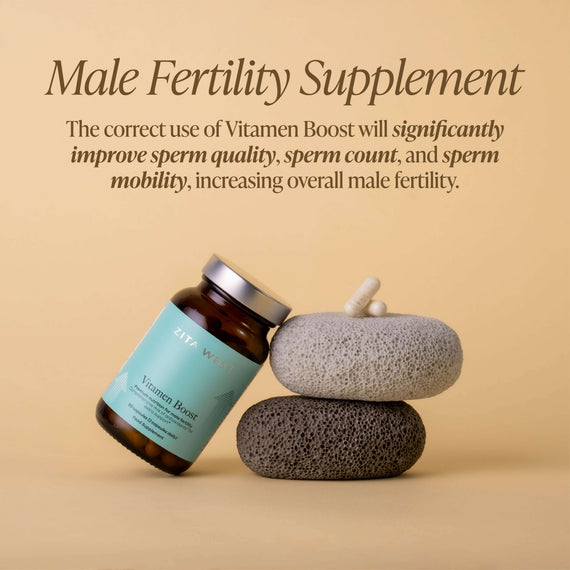 Zita West Vitamen Boost bottle leaning against stacked textured stones with capsules on a warm beige background