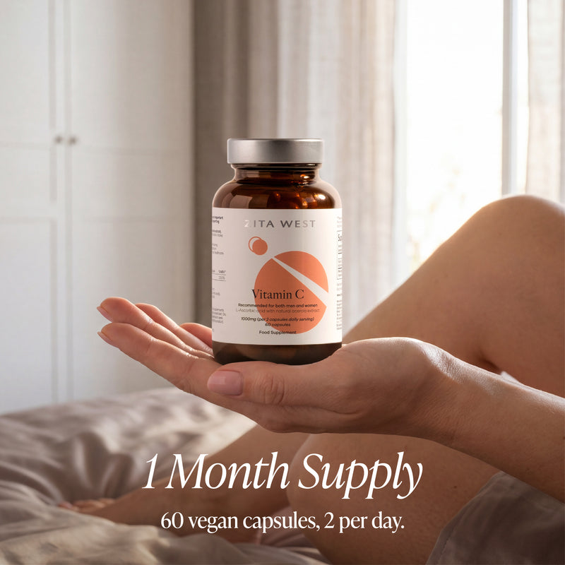 Person holding a bottle of Zita West Vitamin C supplement with a neutral background