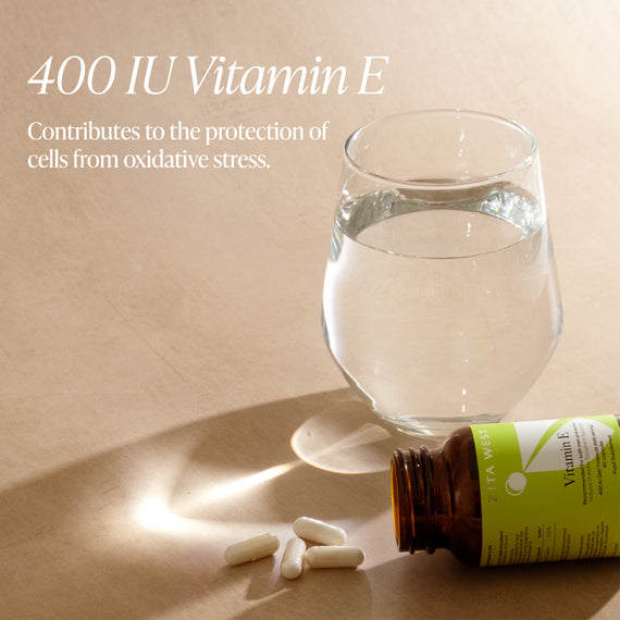 Vitamin E bottle, pills, and glass of water on a beige surface with text about vitamin E.