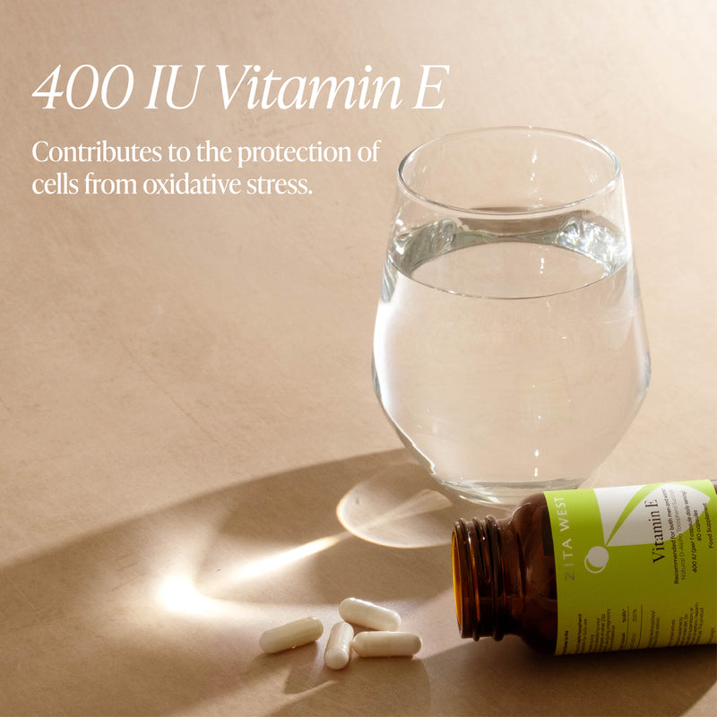 Vitamin E bottle, pills, and glass of water on a beige surface with text about vitamin E.